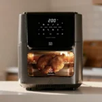 Air Fryer Oven Electrolux EAF90 assando um frango inteiro, visível através do vidro temperado iluminado.