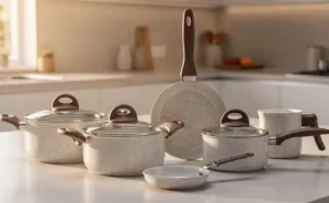 Jogo de panelas Brinox Ceramic Life Smart Plus na cor Vanilla (bege marmorizado) com cabos soft-touch amadeirados, organizado sobre bancada branca.