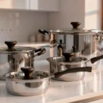 Jogo de panelas Tramontina Solar em aço inox com revestimento interno cerâmico branco, dispostas sobre uma bancada clara de cozinha.